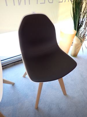 une chaise noire placée devant une fenêtre, avec une plante dans un coin