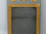un petit miroir avec un cadre doré sur fond blanc