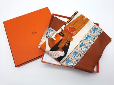 une boîte orange avec une écharpe marron et blanche et une écharpe marron et blanche