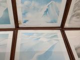 four framed photographs of mountains and clouds are displayed on a table