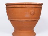 un grand pot en terre cuite posé sur une surface blanche