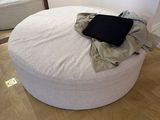 un pouf rond blanc sur lequel est posé un ordinateur portable