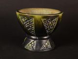 a green and black bowl sitting on a black surface