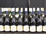 Des bouteilles de vin sont alignées sur une table devant un fond noir.