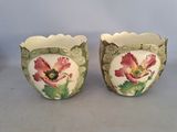 two vases with flowers painted on them sitting on a table