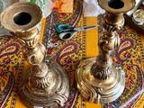 two brass candles on a table with a yellow table cloth