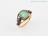 a close up of a ring with a green stone in it