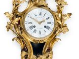 a gold clock on a white wall with a white background