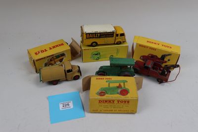 cinq camions miniatures et une boîte posés sur une surface blanche