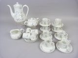 a white tea pot and cups and saucers on a table