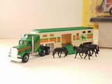 a toy truck with horses and a horse trailer in front of it