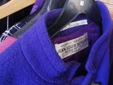 a purple coat hanging on a hanger in a closet