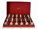 six cuillères en argent dans une boîte rouge posée sur une surface blanche