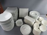 a lot of white plates and bowls on the table