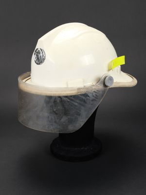 un gros plan d'un casque de chantier blanc posé sur un socle noir