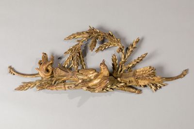 a gold sculpture of a bird on a branch with leaves