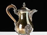 a silver tea pot on a white table with a black background