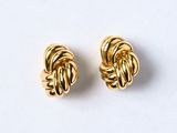 une paire de boucles d'oreilles en forme de nœud, couleur or, posées sur un fond blanc