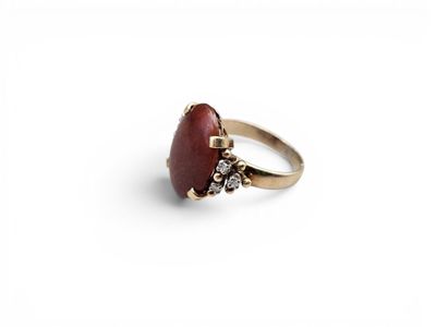 a close up of a red stone ring on a white surface