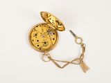 a small gold pocket watch with a chain around it