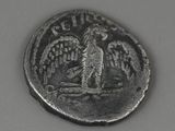 une vieille pièce de monnaie sur laquelle est représenté un oiseau, posée sur une table