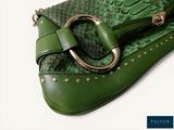 a green purse with a metal ring on top of it