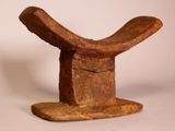 an old wooden sculpture of a hat on a stand on a white surface