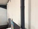 a black stove in the corner of a room next to a wall