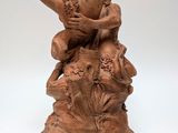 statue of a man sitting on a rock with a flower in his hand