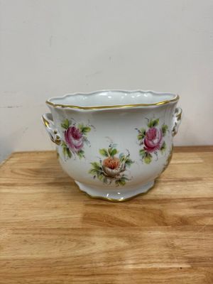 an image of a white bowl with pink flowers on it on a wooden table