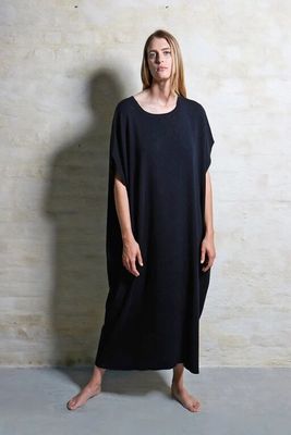 the woman is standing in front of a wall wearing a black dress