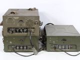 two old military radio equipment sitting on a white surface