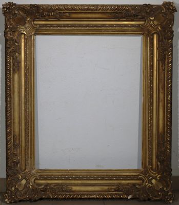 un cadre photo doré posé sur une table près d'un mur