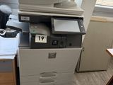 a printer sitting on top of a desk next to a chair
