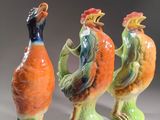 trois figurines en céramique représentant des oiseaux colorés sur un fond gris