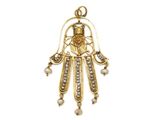 un gros plan d'un pendentif hamsa en or et perles sur fond blanc