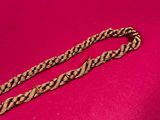 a close up of a gold chain on a pink background