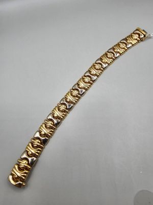 gros plan d'un bracelet en or sur une surface blanche