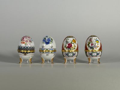 Quatre œufs de couleurs différentes sont alignés sur une table