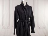 Le manteau est noir et est muni d'une ceinture.
