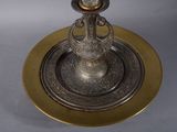 a silver and gold plate with a candle on it