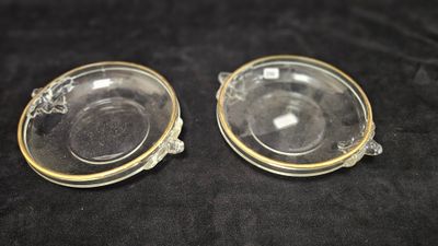 two clear glass dishes with gold rims on a black surface