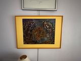 a vase sitting on a table next to a painting on the wall