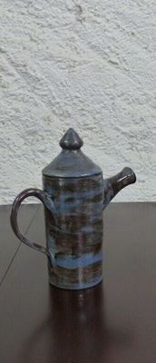 a small teapot sitting on a table with a white wall in the background