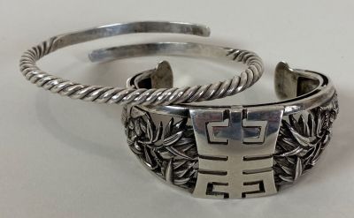 pair of silver cuff bracelets on a white surface with a white background