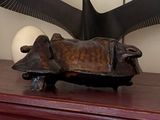 a sculpture of a cow laying on top of a wooden table