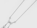 un gros plan d'un collier en diamants posé sur une surface blanche