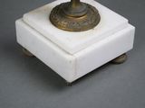 a small white marble box with a brass candle on it