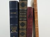 several old books are lined up on a white surface
