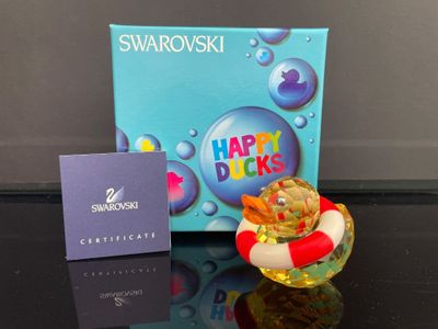 une petite figurine représentant un canard avec un gilet de sauvetage posé devant lui